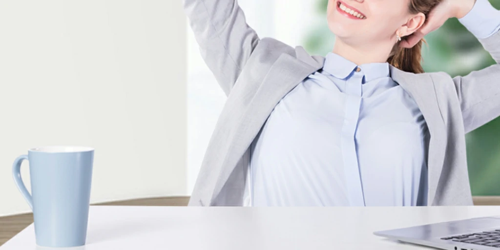 businesswoman stretching at desk with coffee mug