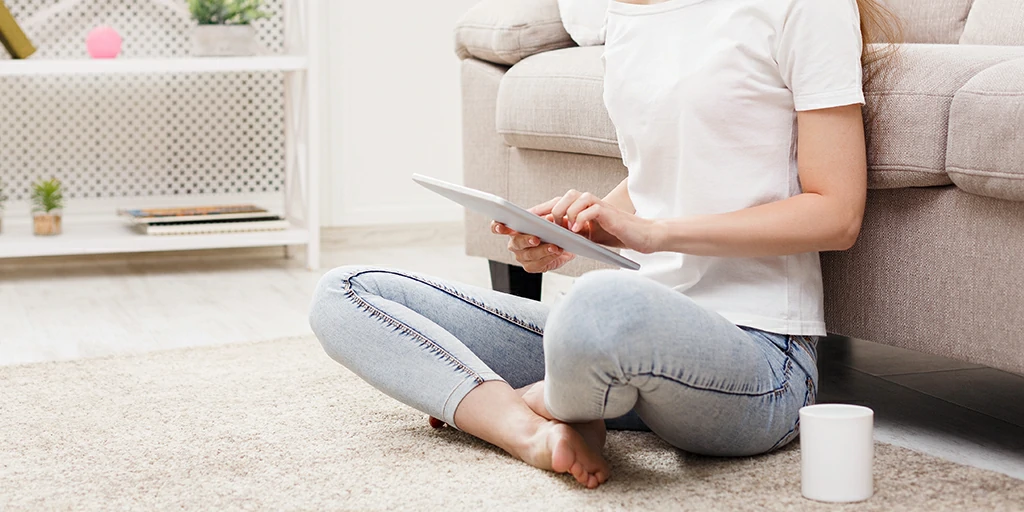 woman sitting cross-legged on chair using tablet