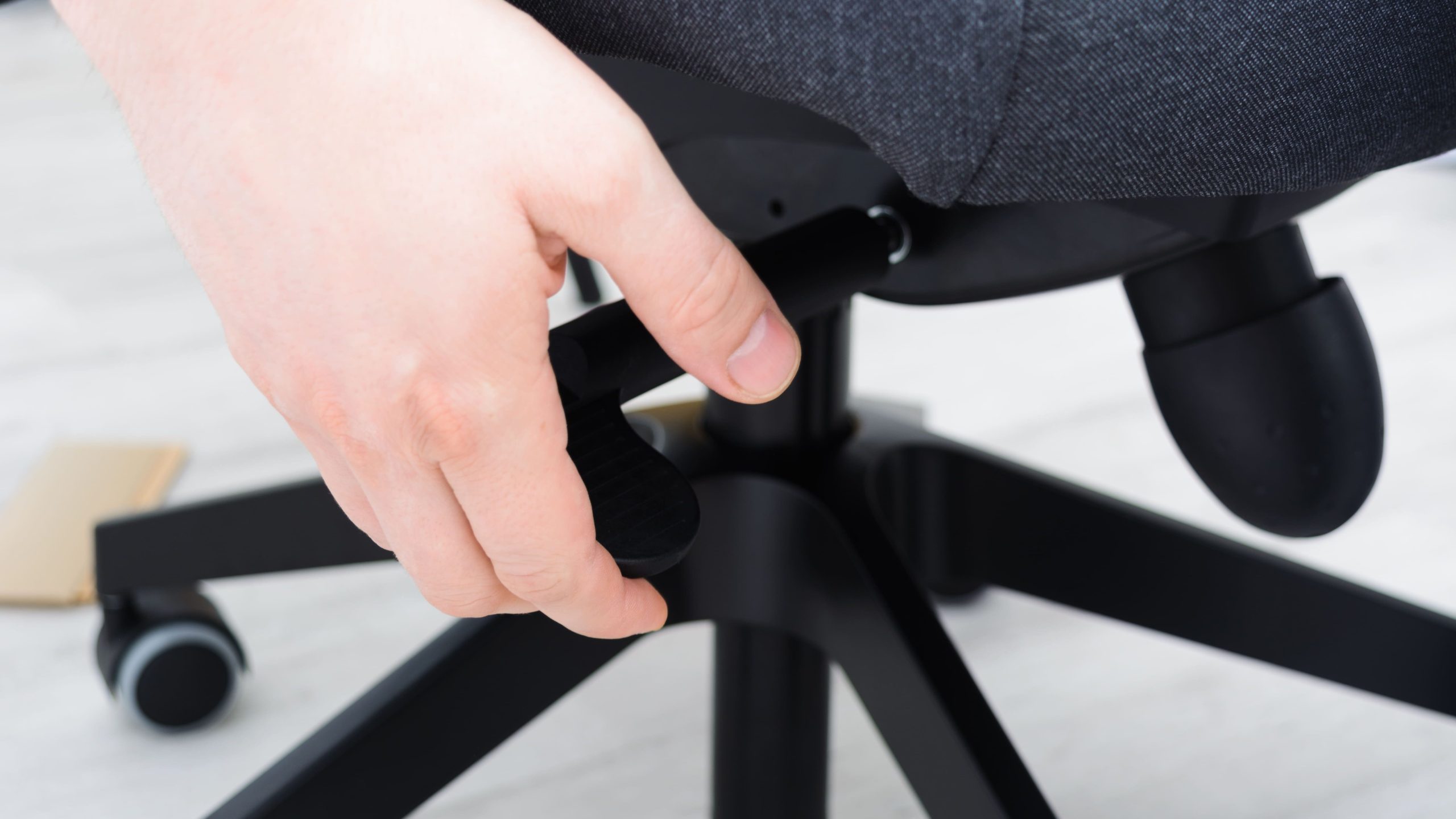 Employee adjusting ergonomic chair seat height for proper posture